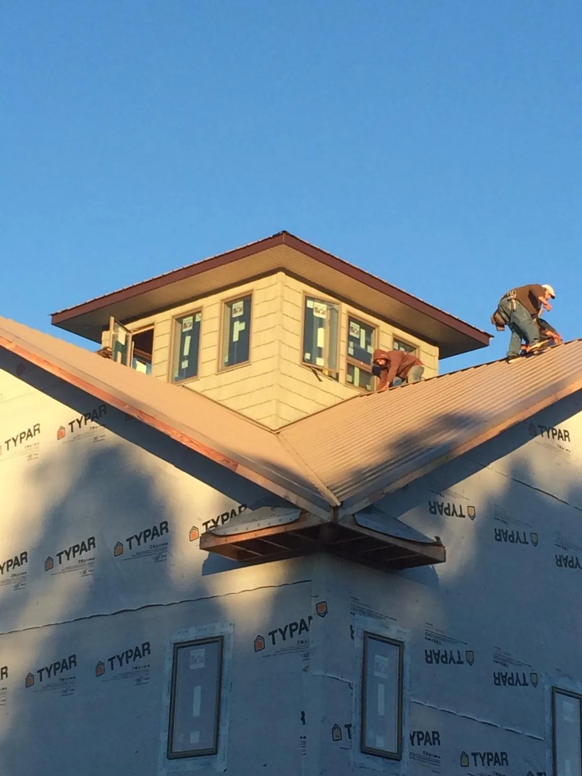 Roofers working around a rooftop cupola on a new metal roof at sunset — Roof Waterproofing in Hartford by Roofing Brothers
